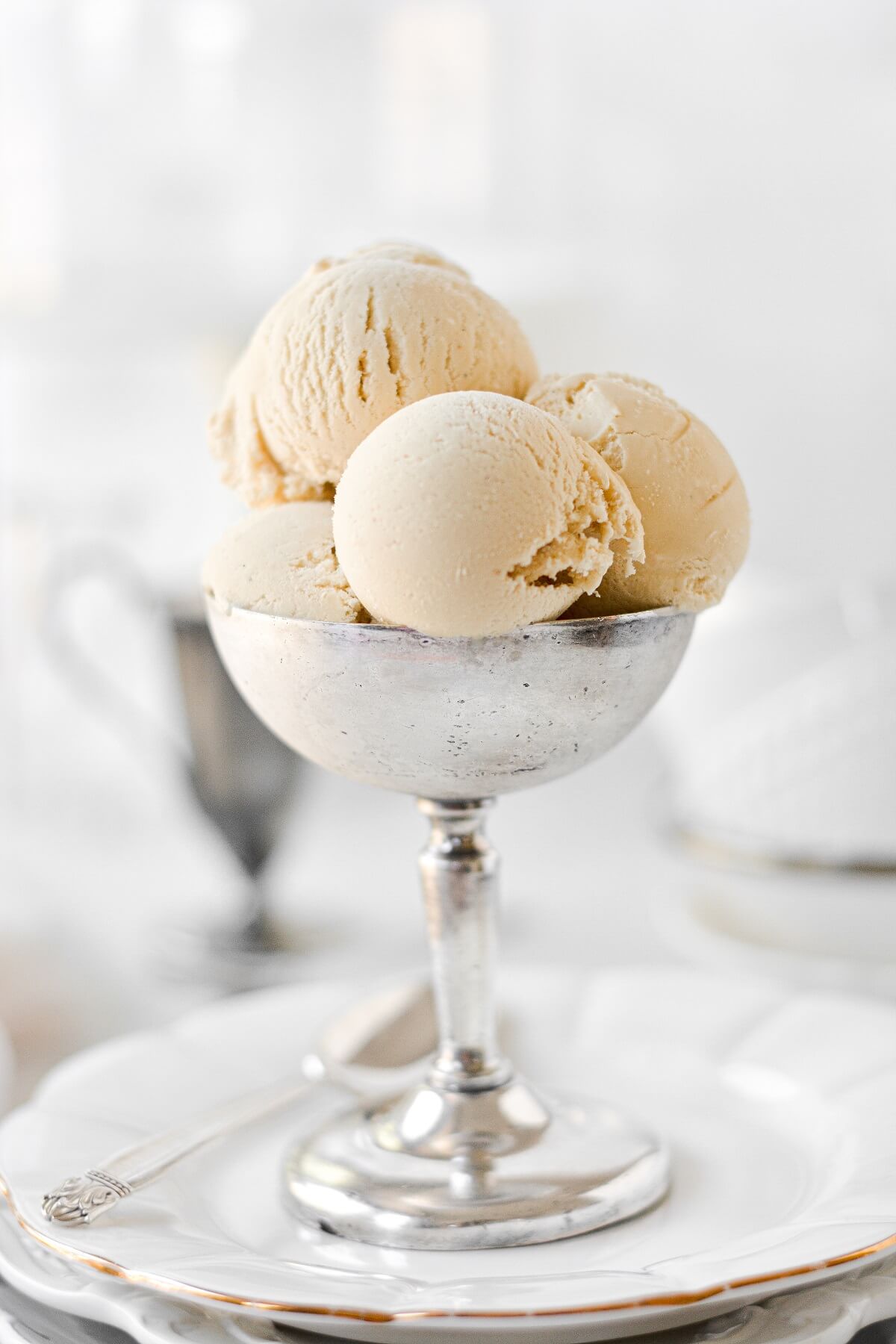 Scoops of brown sugar ice cream in a silver footed bowl.