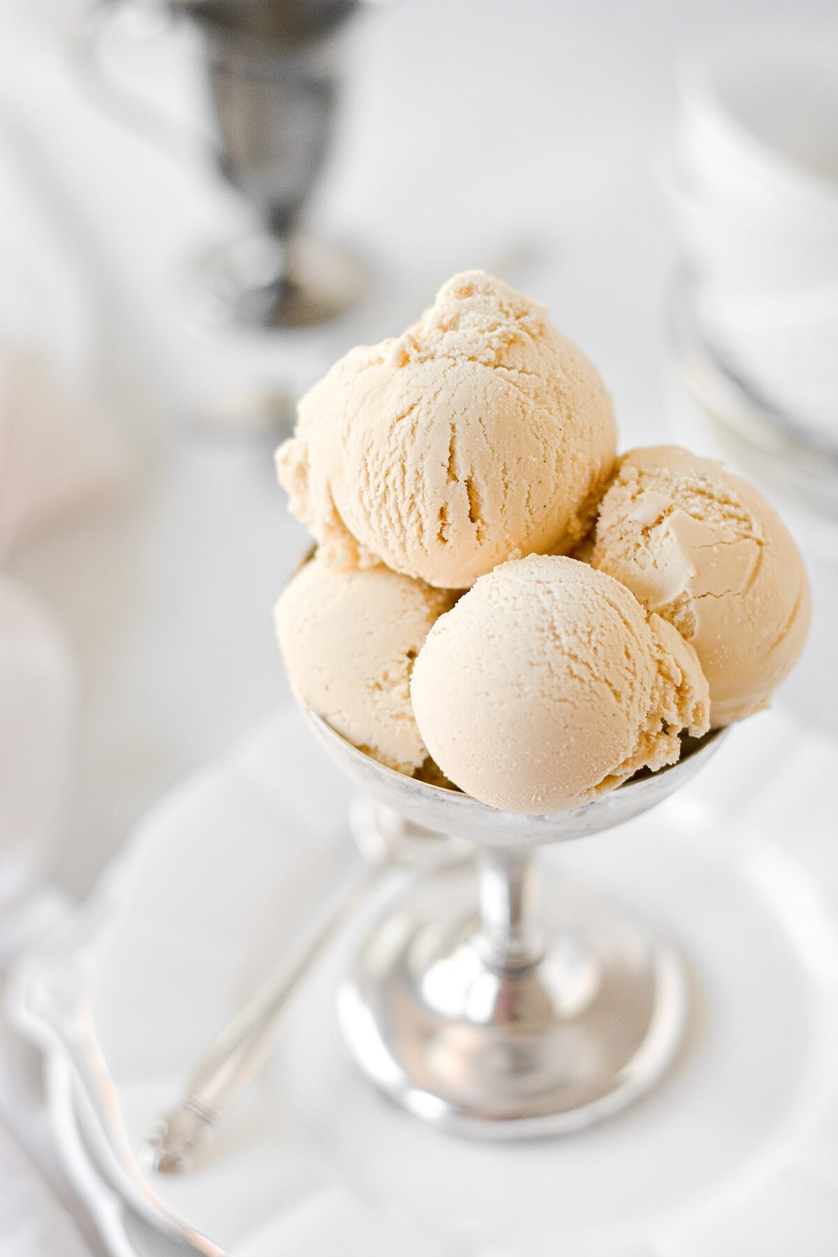 Scoops of brown sugar ice cream in a silver footed bowl.