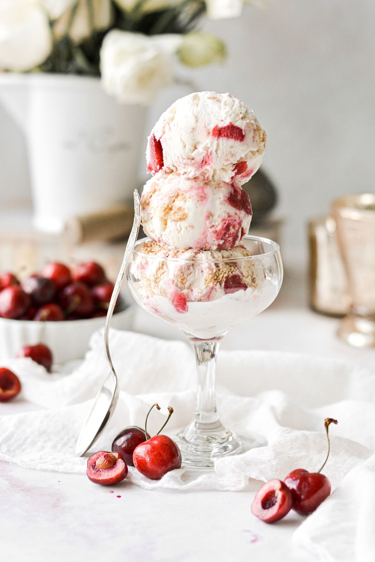 Scoops of cherry cheesecake swirl ice cream stacked in a cocktail glass.