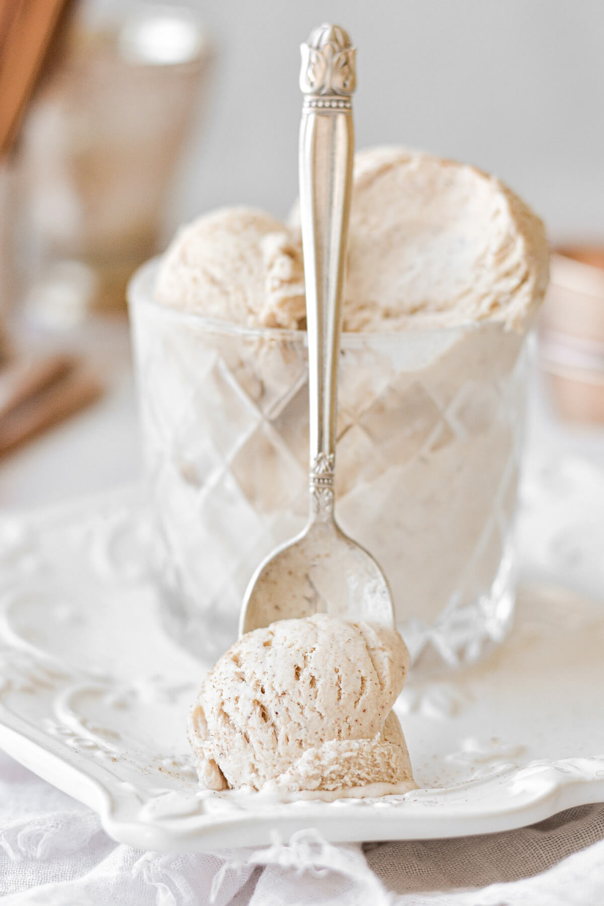 A spoonful of cinnamon ice cream, leaning against a glass.