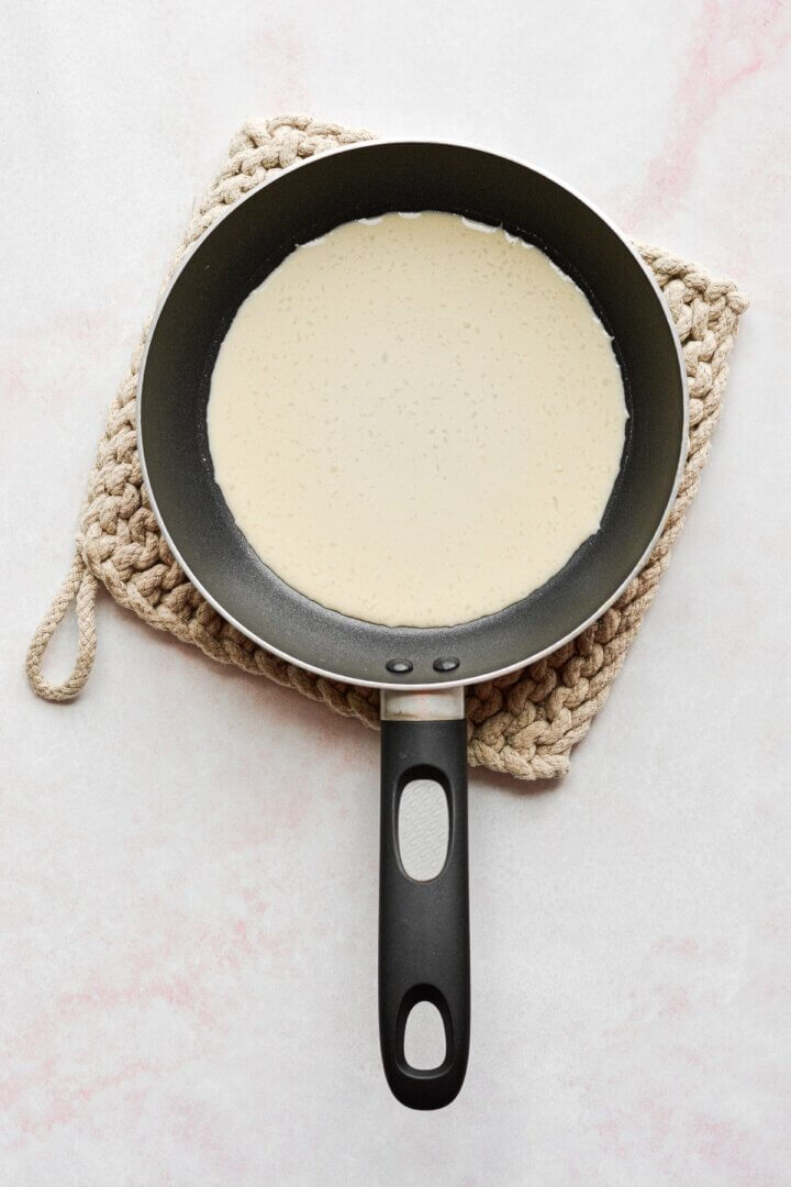 A crepe cooking in a skillet.