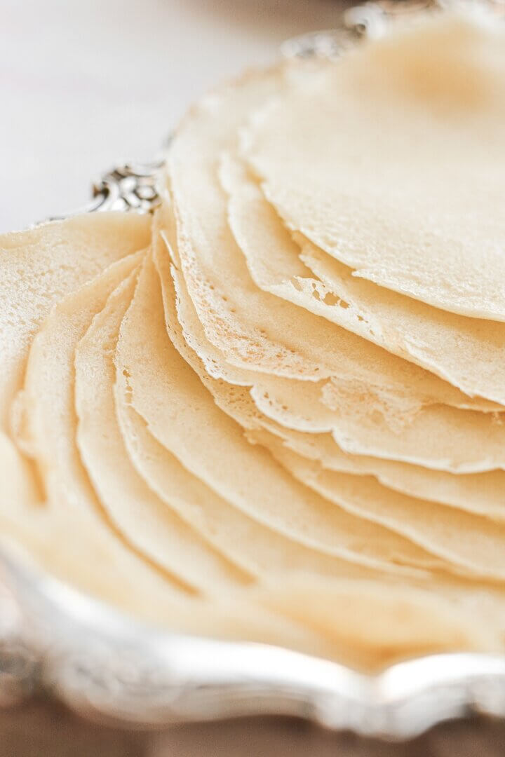 Crepes stacked on a silver tray.