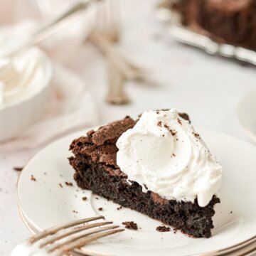 A slice of flourless chocolate cake topped with bourbon whipped cream.