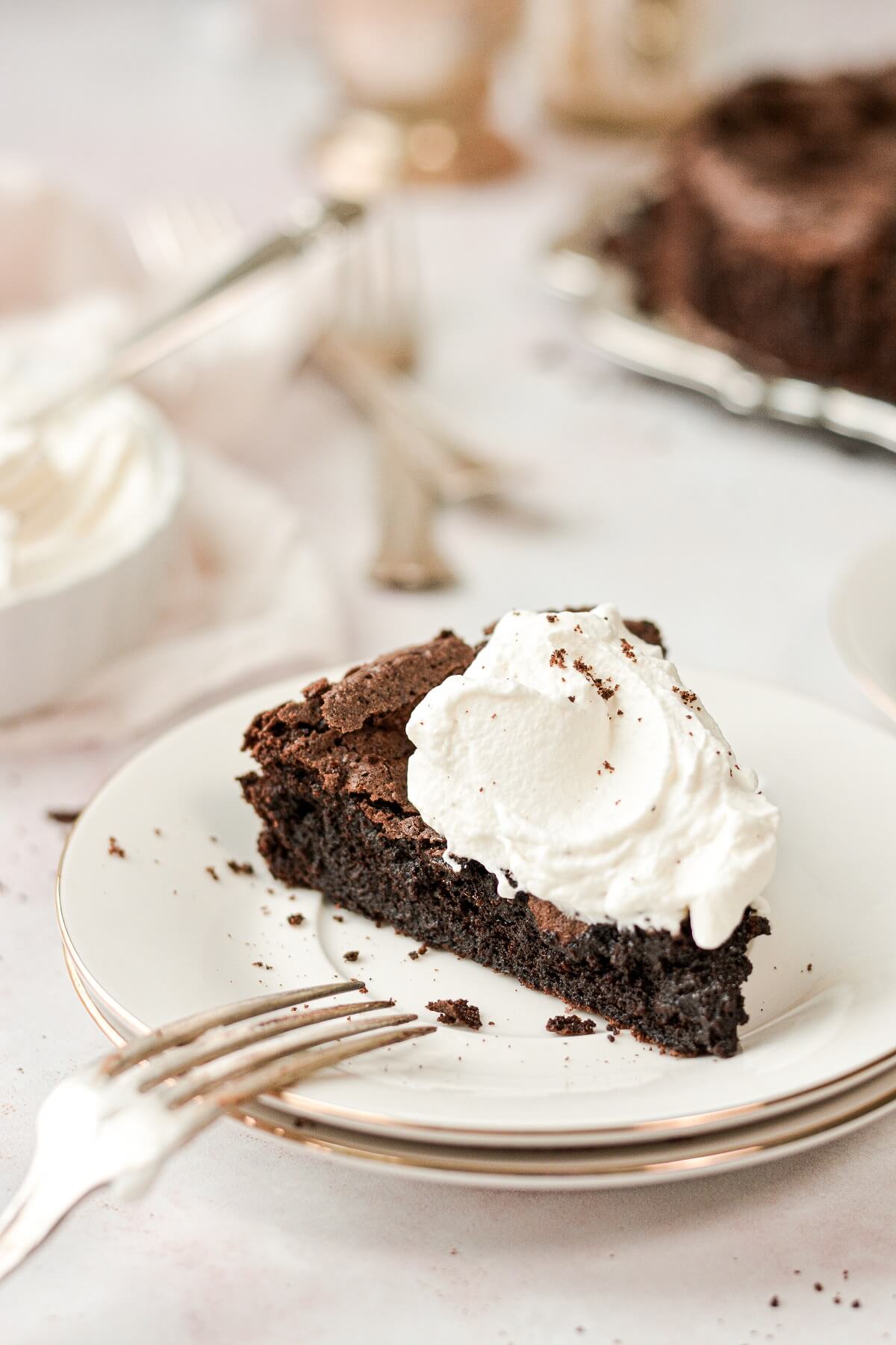 A slice of flourless chocolate cake topped with bourbon whipped cream.