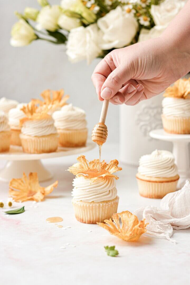 Honey being drizzled over a honey lemon cupcake.