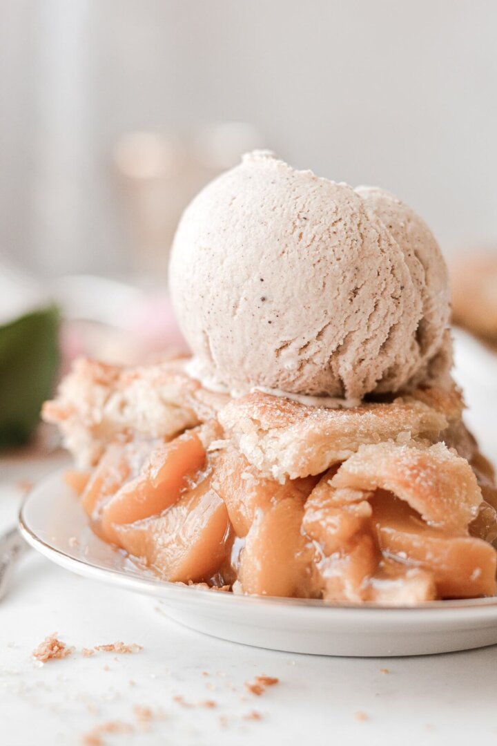 A slice of peach pie topped with a scoop of cinnamon ice cream.