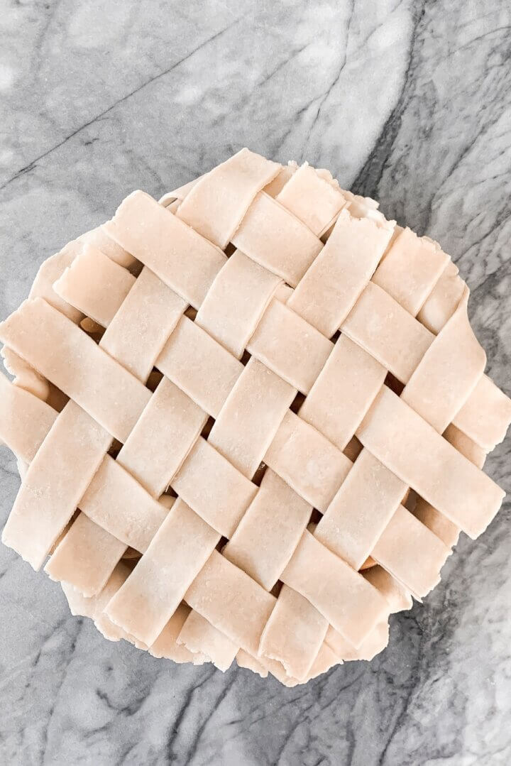 Unbaked strips of pie dough, arranged in a lattice pattern.