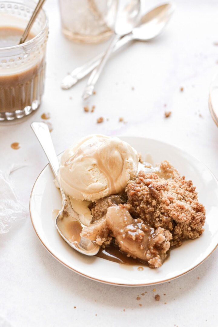 Apple crumble with a scoop of ice cream drizzled with caramel sauce.