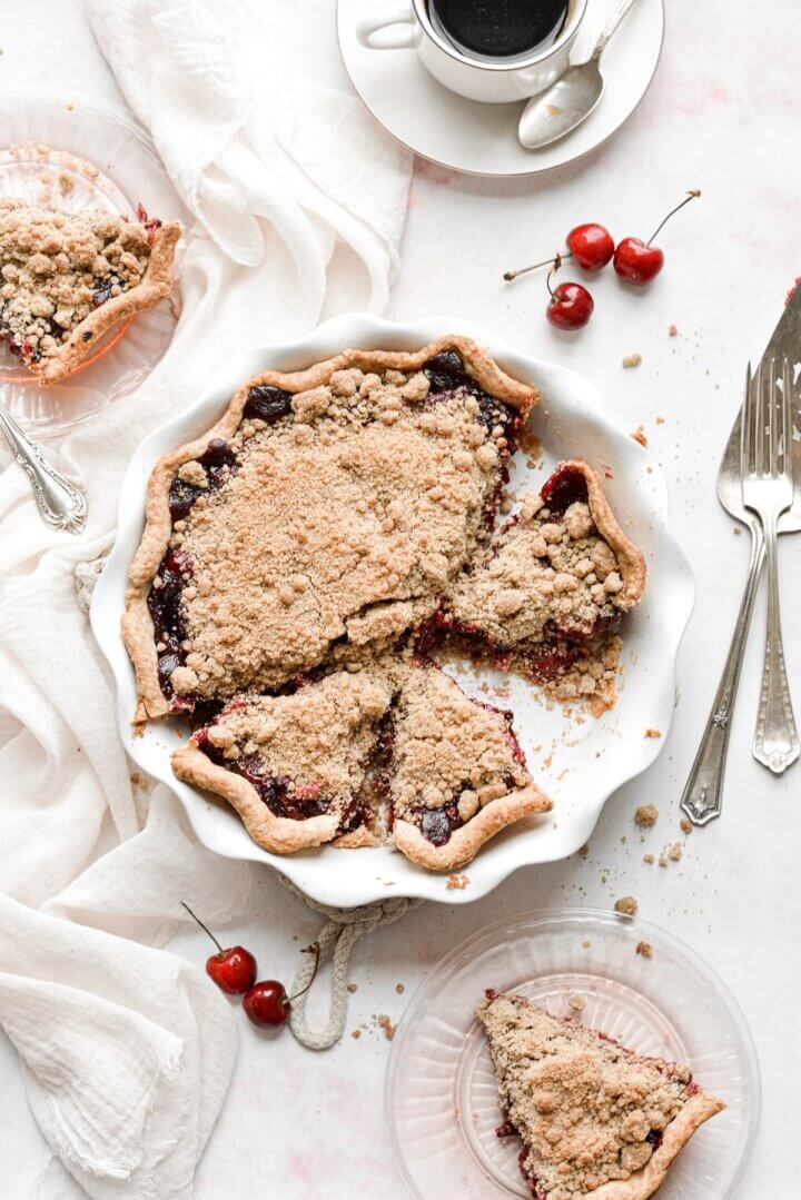 Cherry crumb pie with several slices cut.