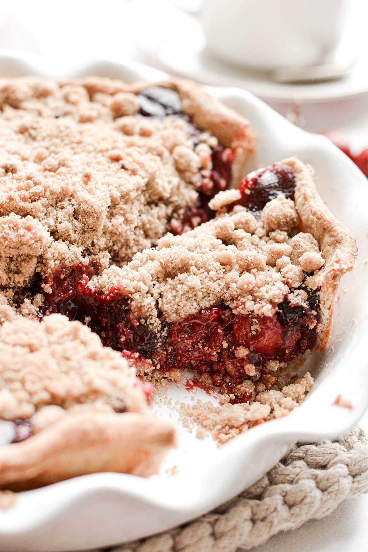 Cherry crumb pie with several slices cut.