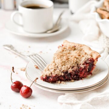 A slice of cherry crumb pie with a cup of coffee.