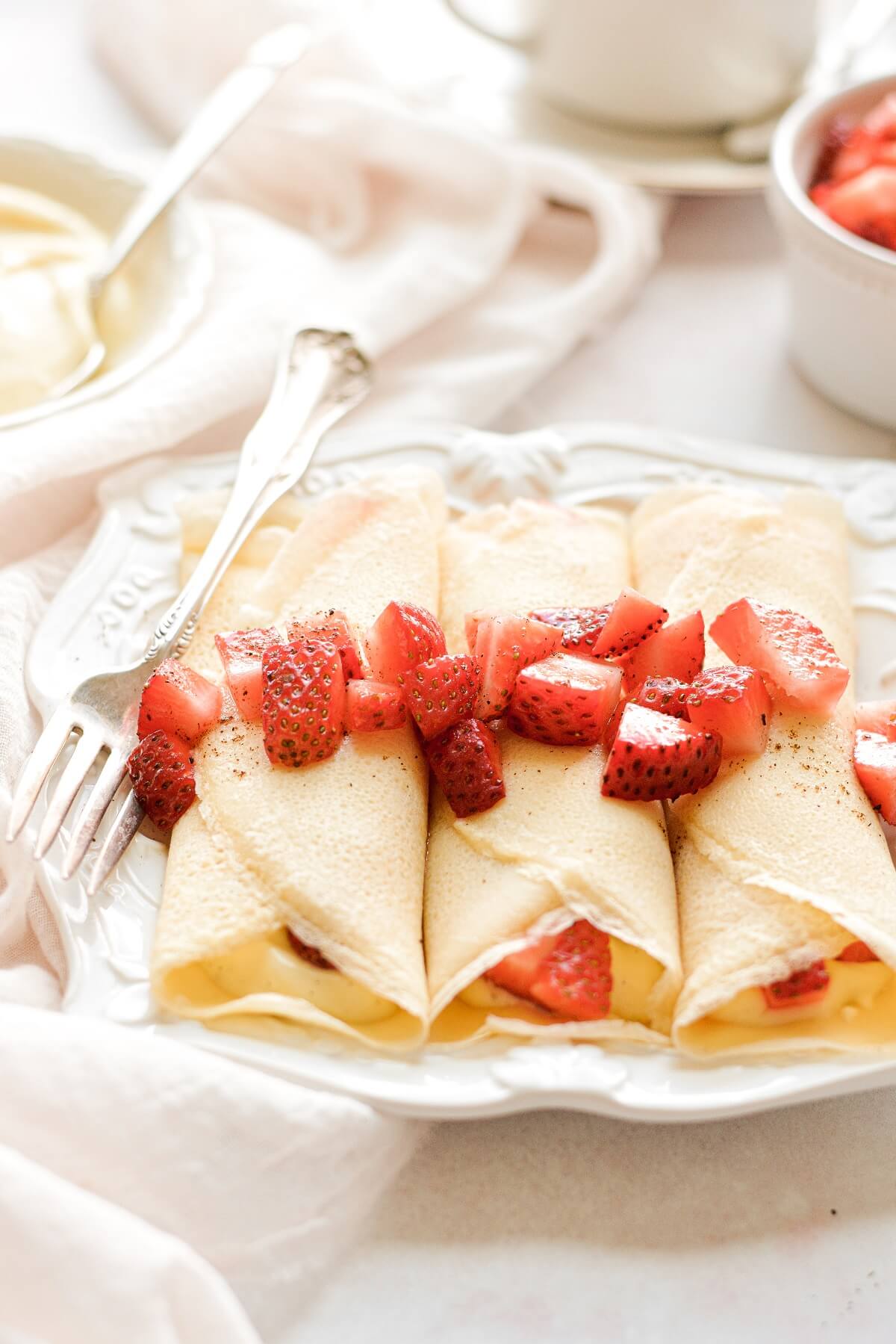 Three homemade crepes, topped with strawberries.
