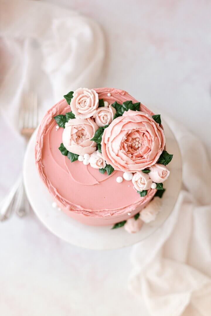 Buttercream flowers on a pink frosted cake.