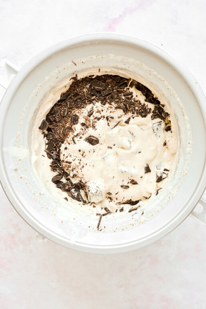 Pistachio ice cream in an ice cream maker, swirled with brownies and chopped chocolate.