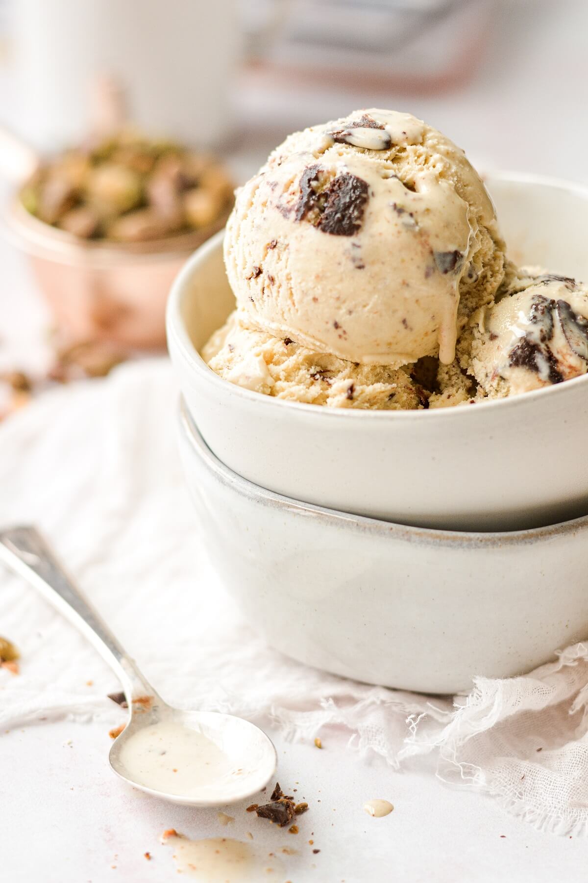 Pistachio browni chunk ice cream, next to a spoon dripping with ice cream.