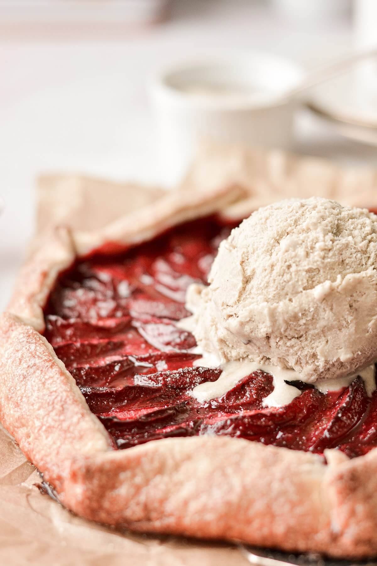 Closeup of a plum galette, topped with a scoop of melting ice cream.
