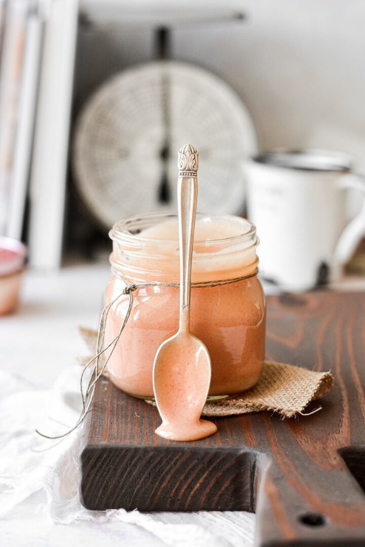 A jar of rhubarb curd with a spoon resting against the jar.