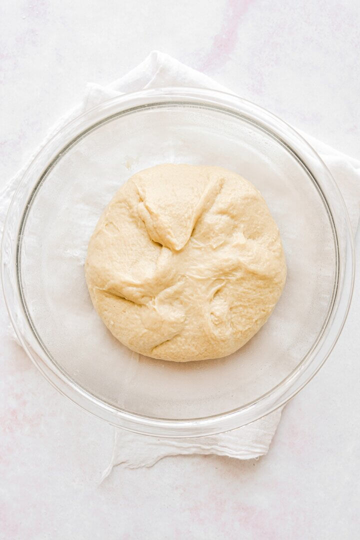 A glass bowl with dough rising for rolls.