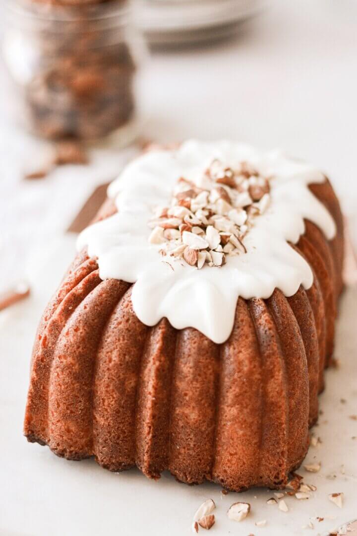 A loaf of almond pound cake with almond icing and chopped almonds.