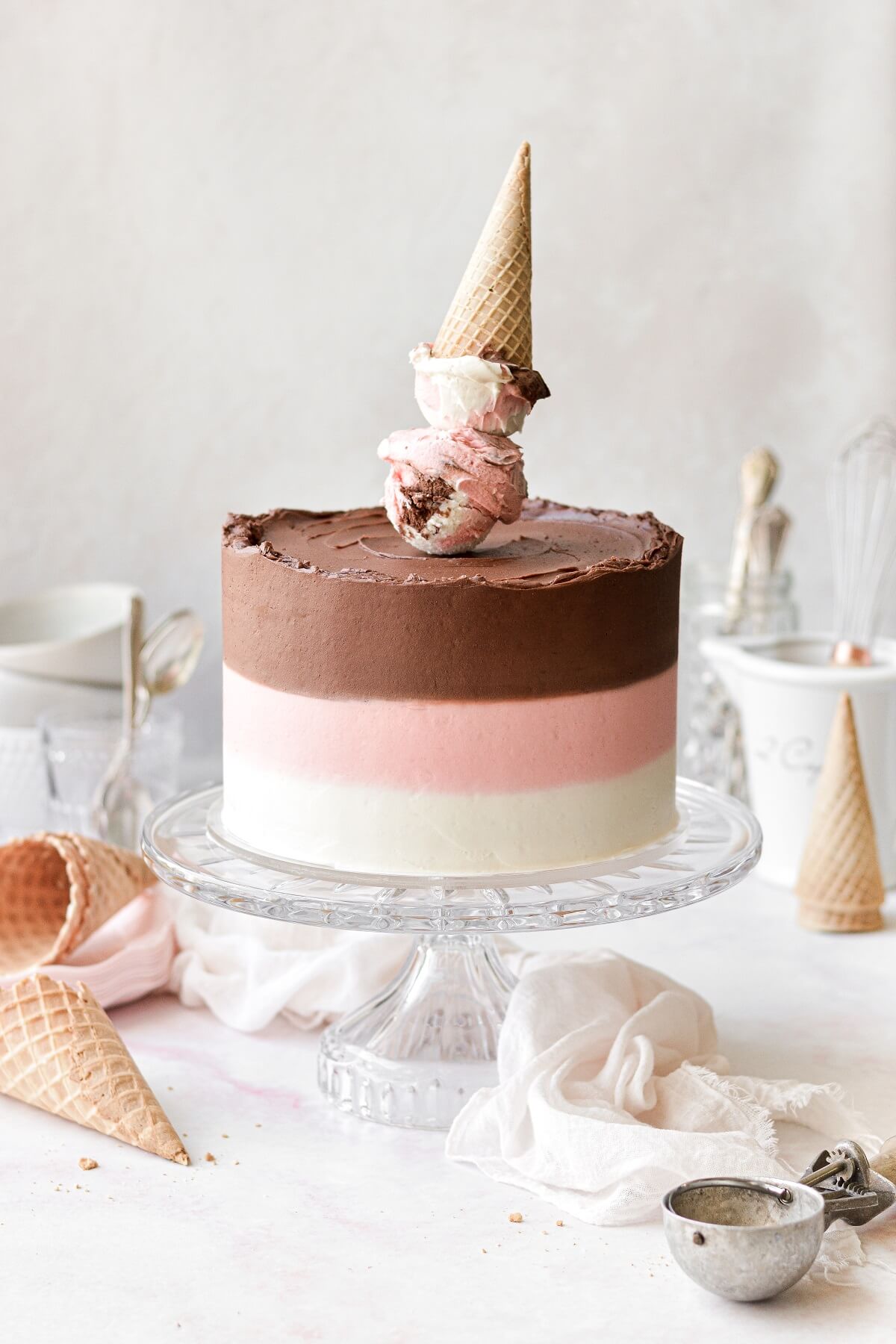 Neapolitan cake with striped buttercream and an ice cream cone cake topper.