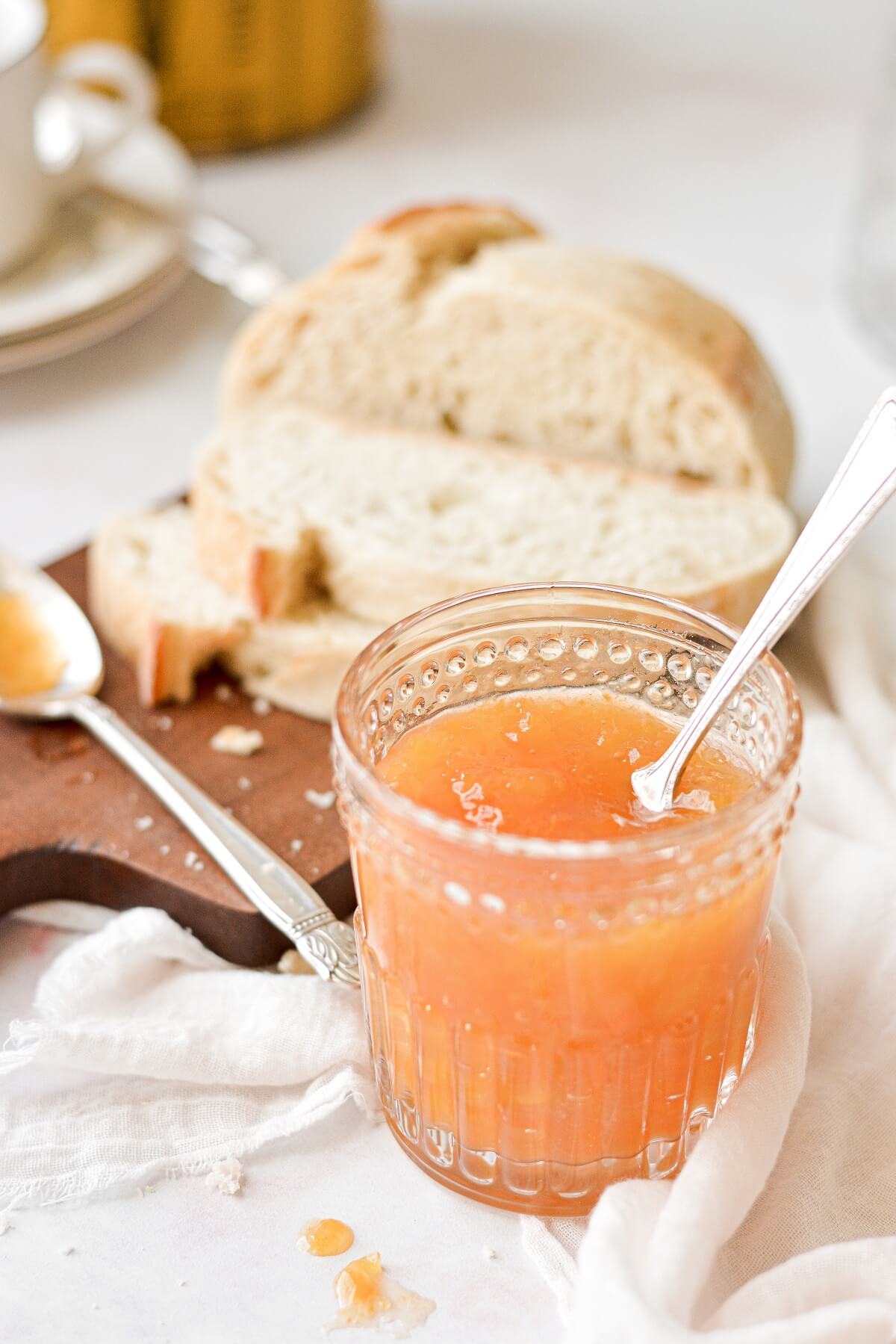 A jar of peach apricot jam, next to a loaf of sliced bread.