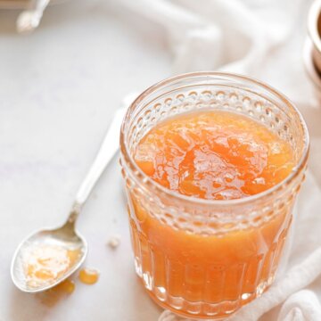 A glass jar of peach apricot jam.