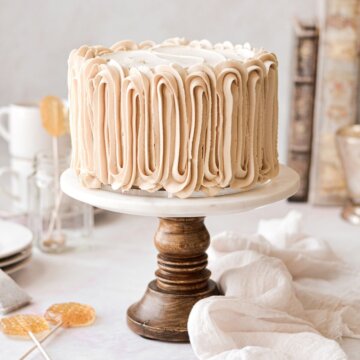 Chai tea spice cake with piped buttercream on a marble and wood cake stand.