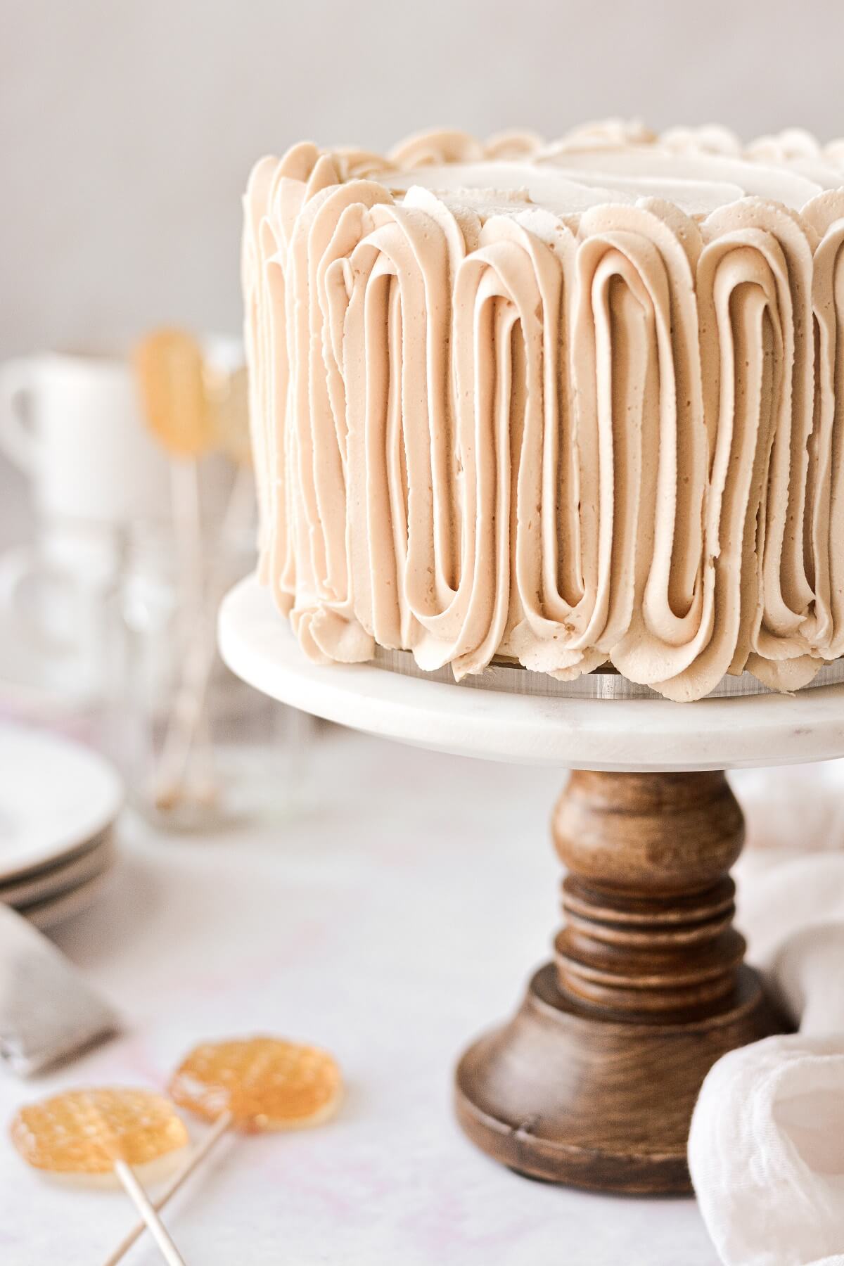 Chai tea spice cake with piped buttercream on a marble and wood cake stand.