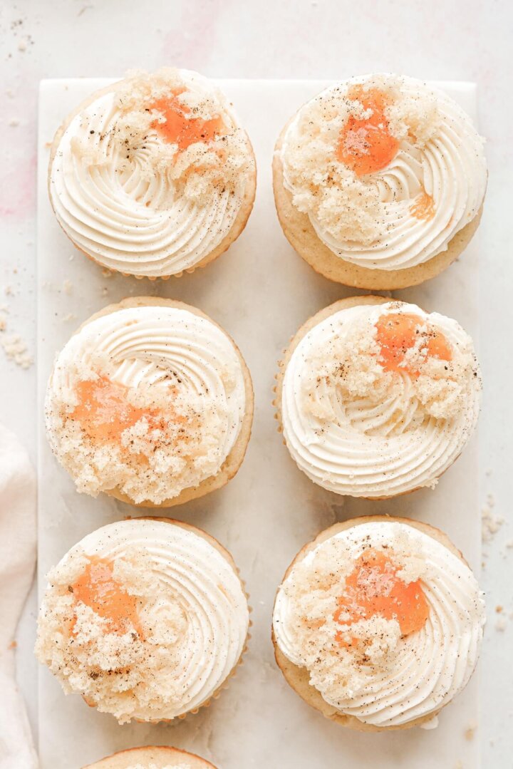Peach cupcakes with swirls of buttercream and peach jam on top.