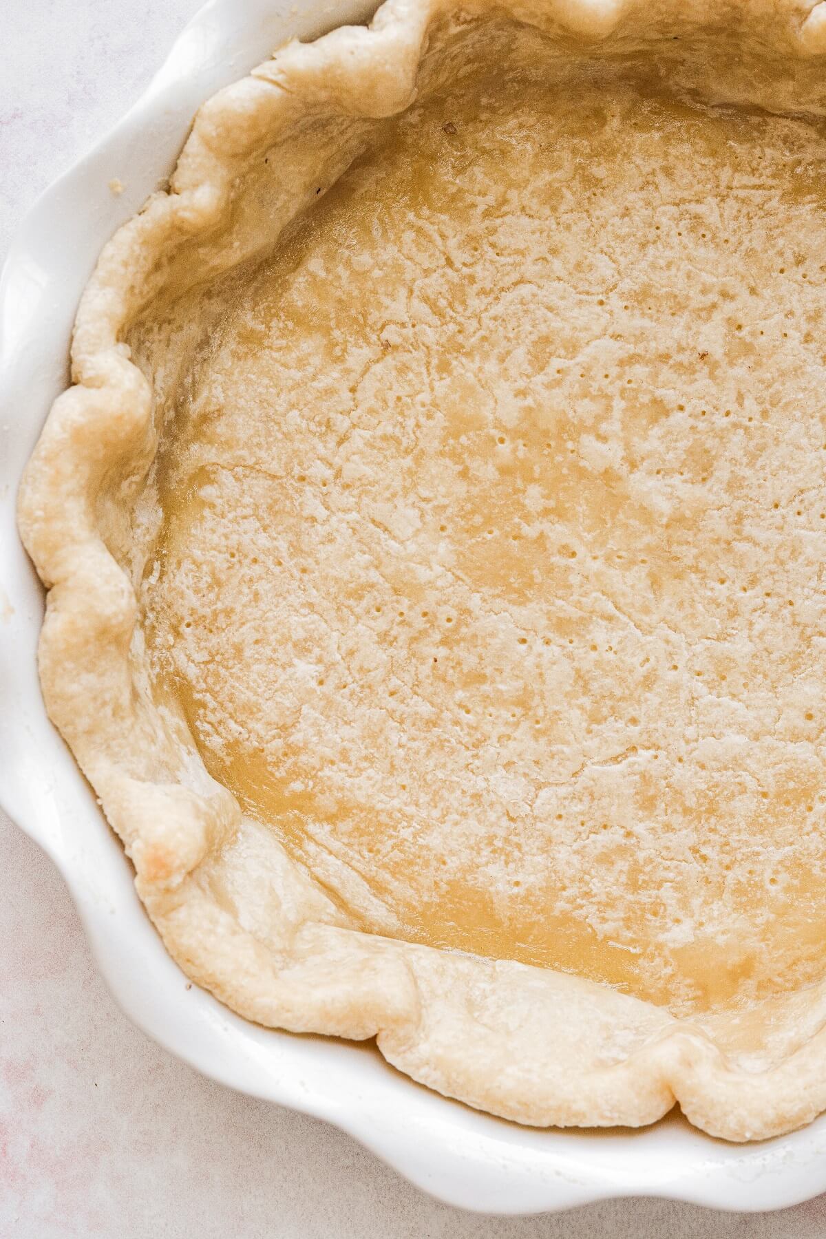 A pre-baked pie crust in a white pie pan.