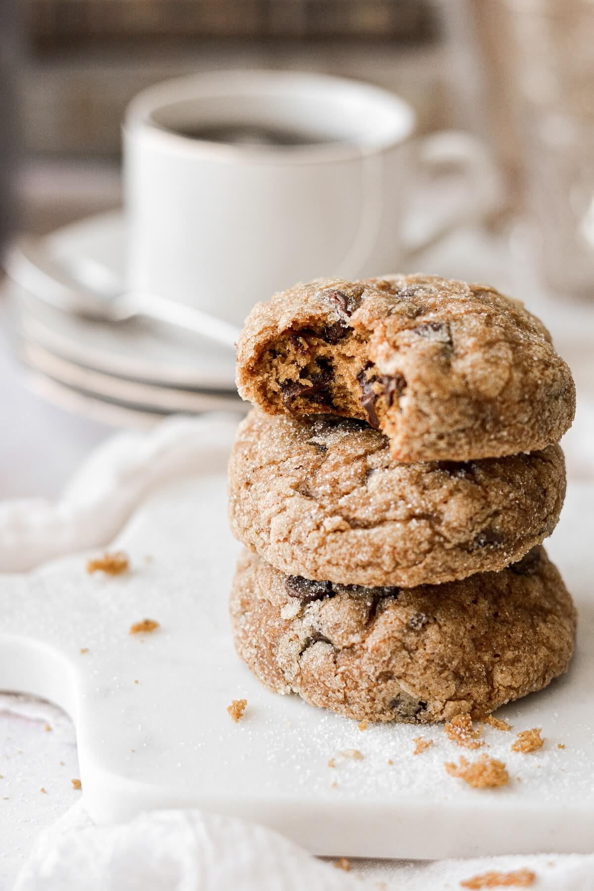 A stack of pumpkin chocolate chip cookies, one with a bite taken.