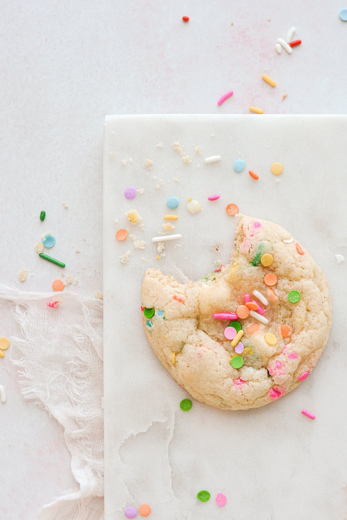 A sprinkle cookie with a bite taken.
