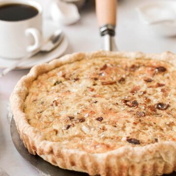 Baked quiche Lorraine next to a cup of coffee.