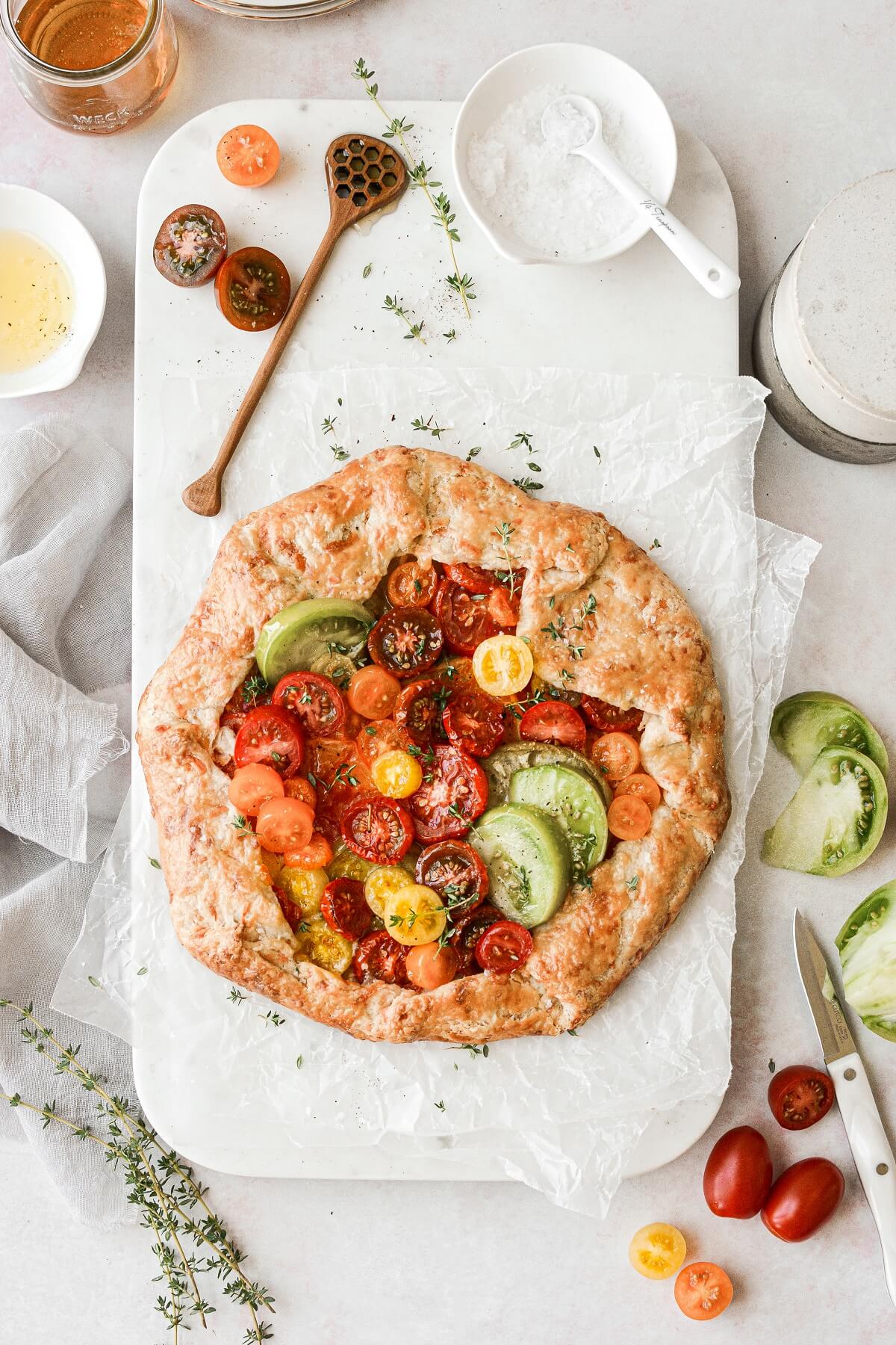 A tomato galette made with heirloom tomatoes on a white marble serving board.