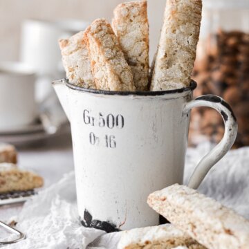 Almond biscotti standing up in a vintage measuring cup.