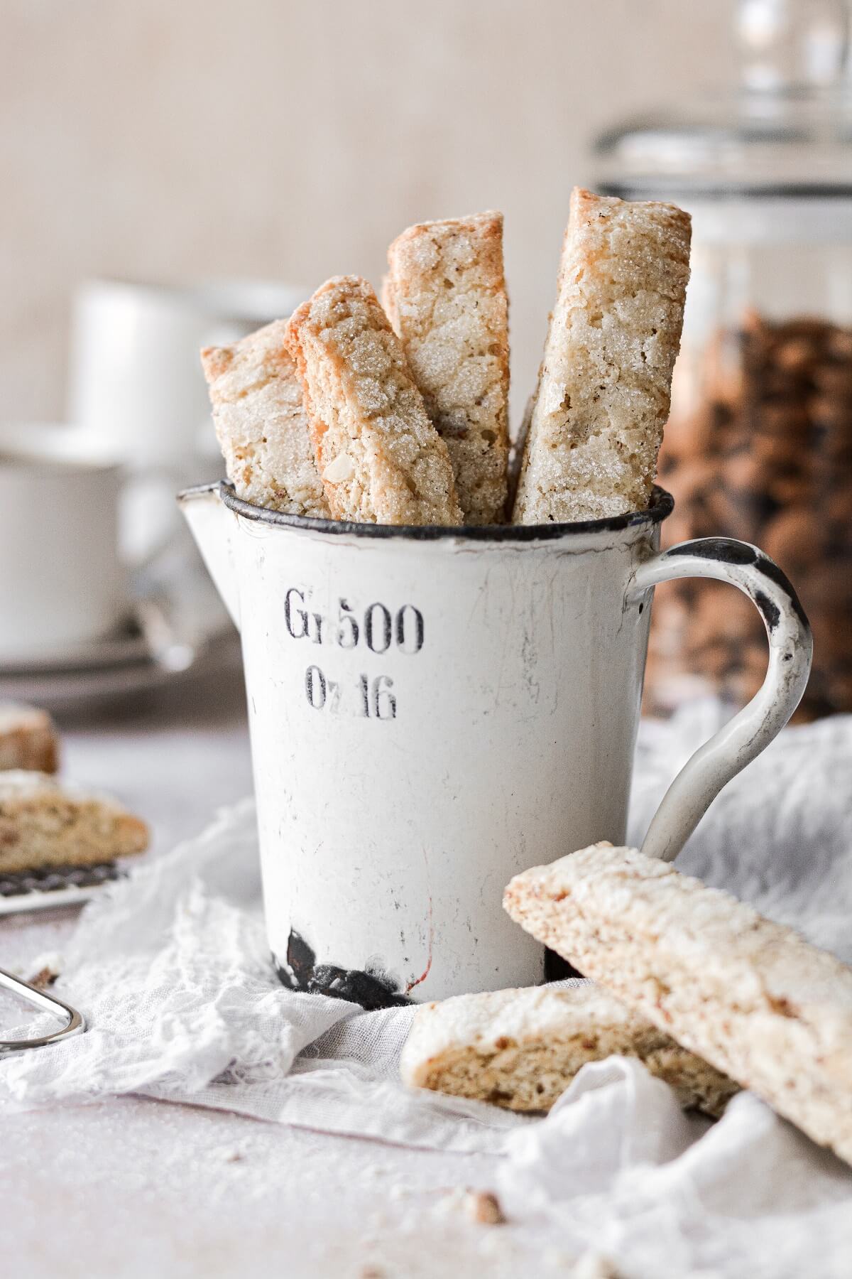 Almond biscotti standing up in a vintage measuring cup.
