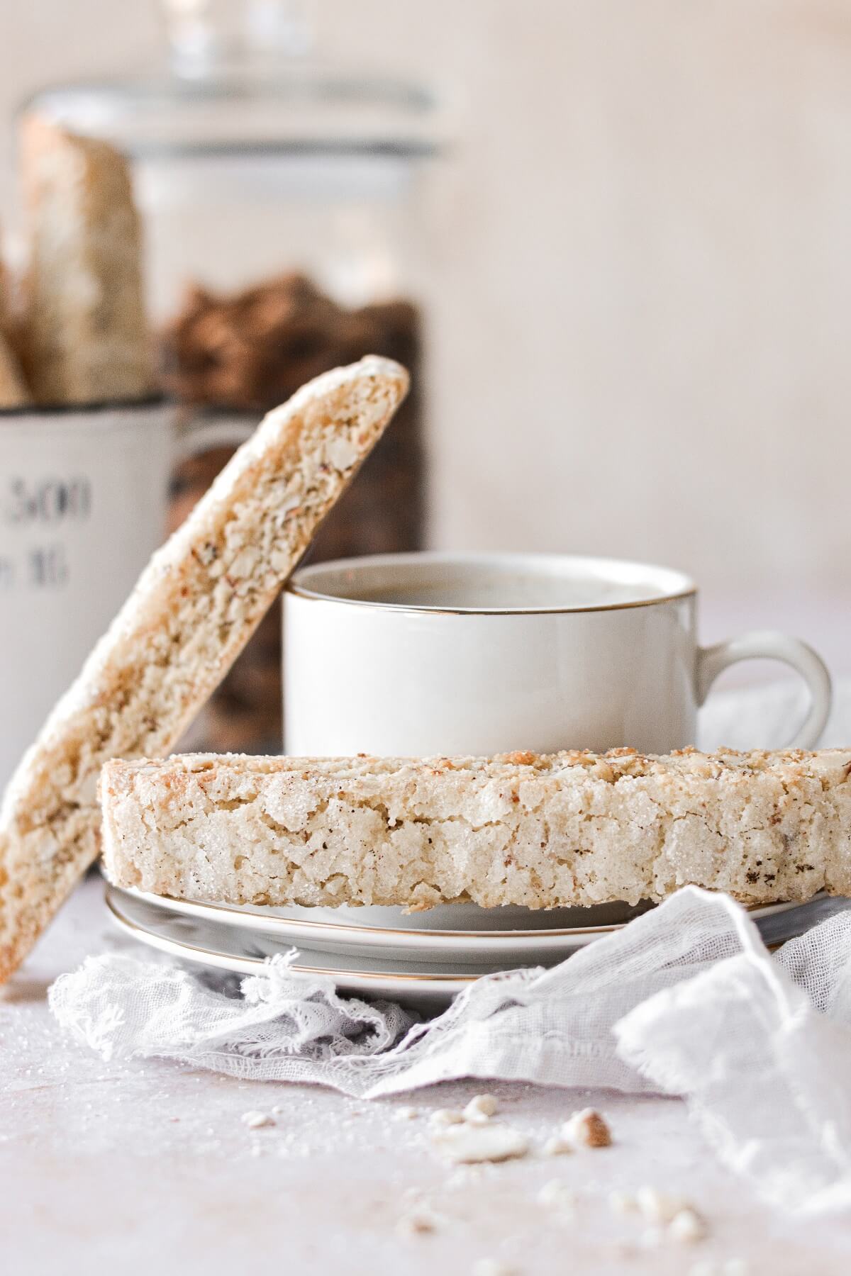 Almond biscotti on a saucer with a cup of coffee.