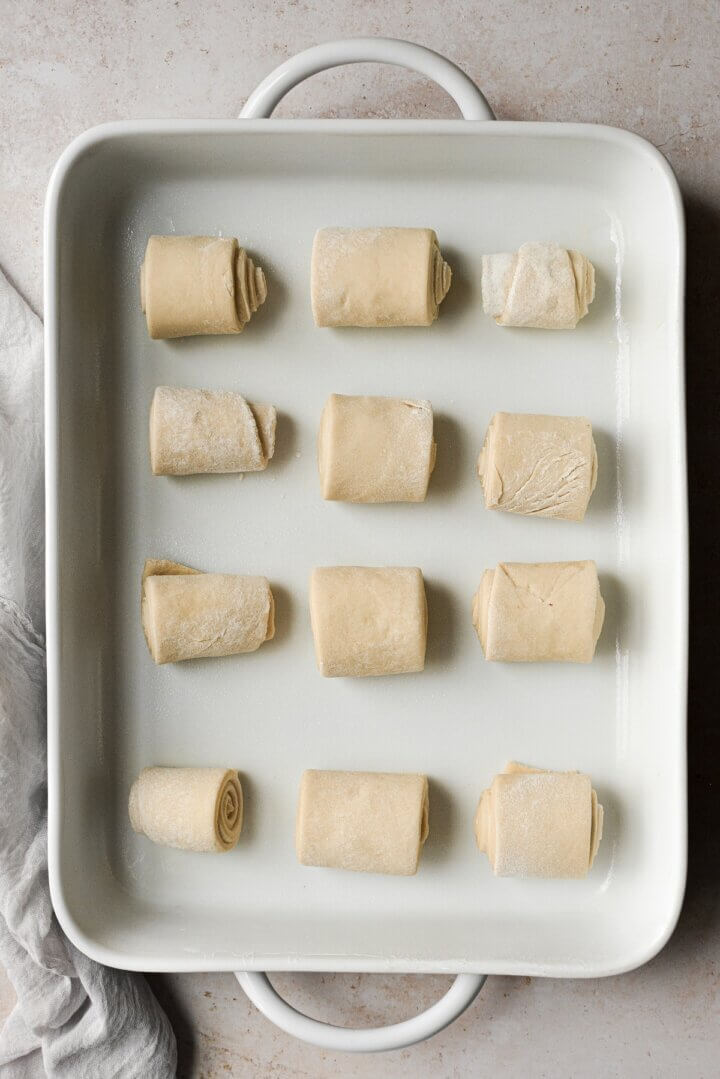 Unbaked Parker House rolls arranged in a white baking dish.