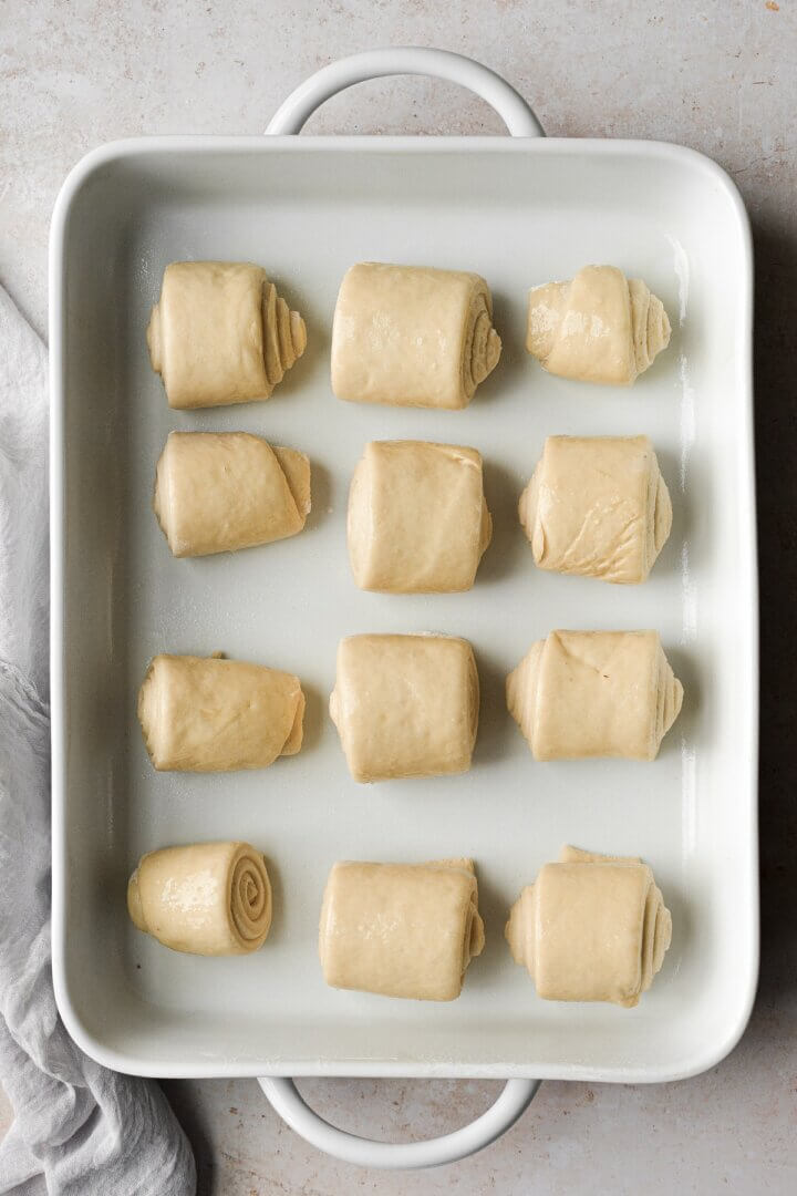 Rolls in a white baking dish about to be baked.