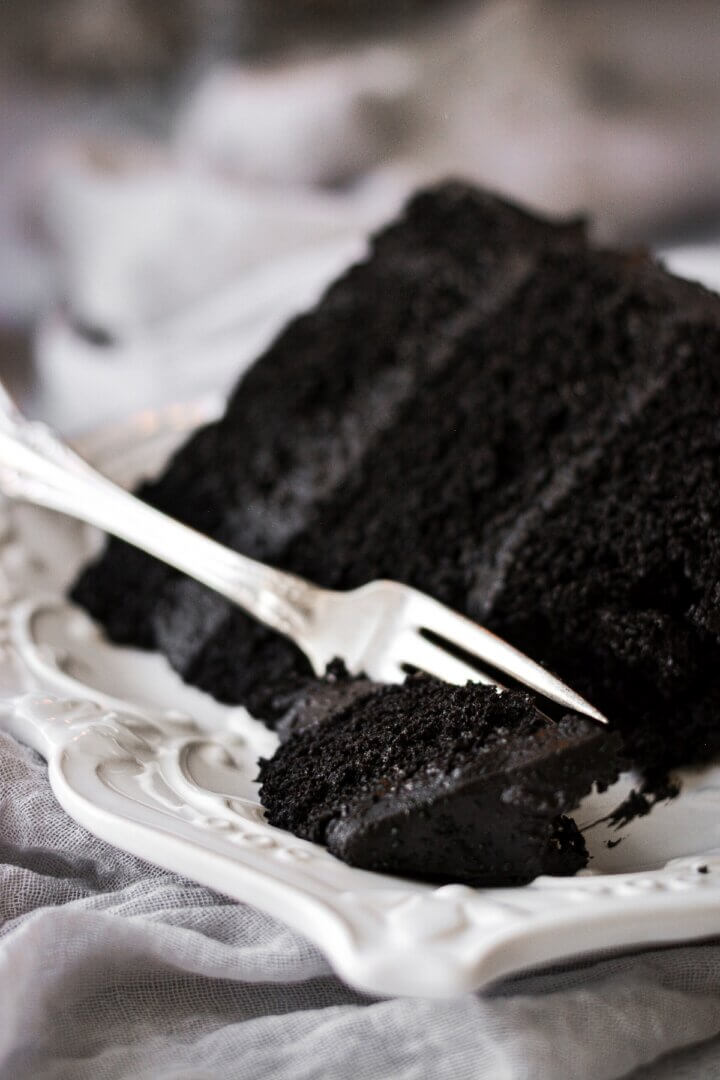 A slice of black velvet cake with a bite cut.