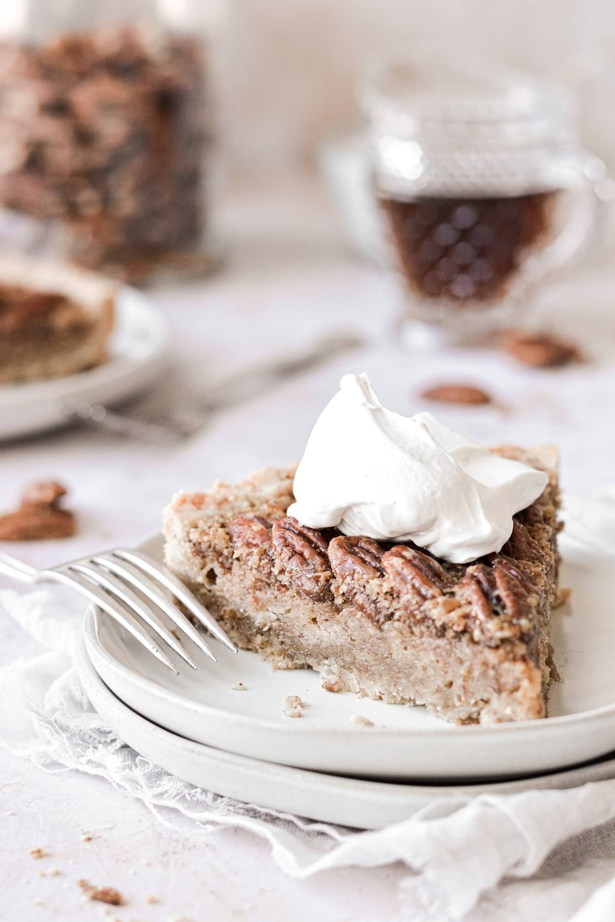 A slice of maple pecan tart topped with whipped cream.