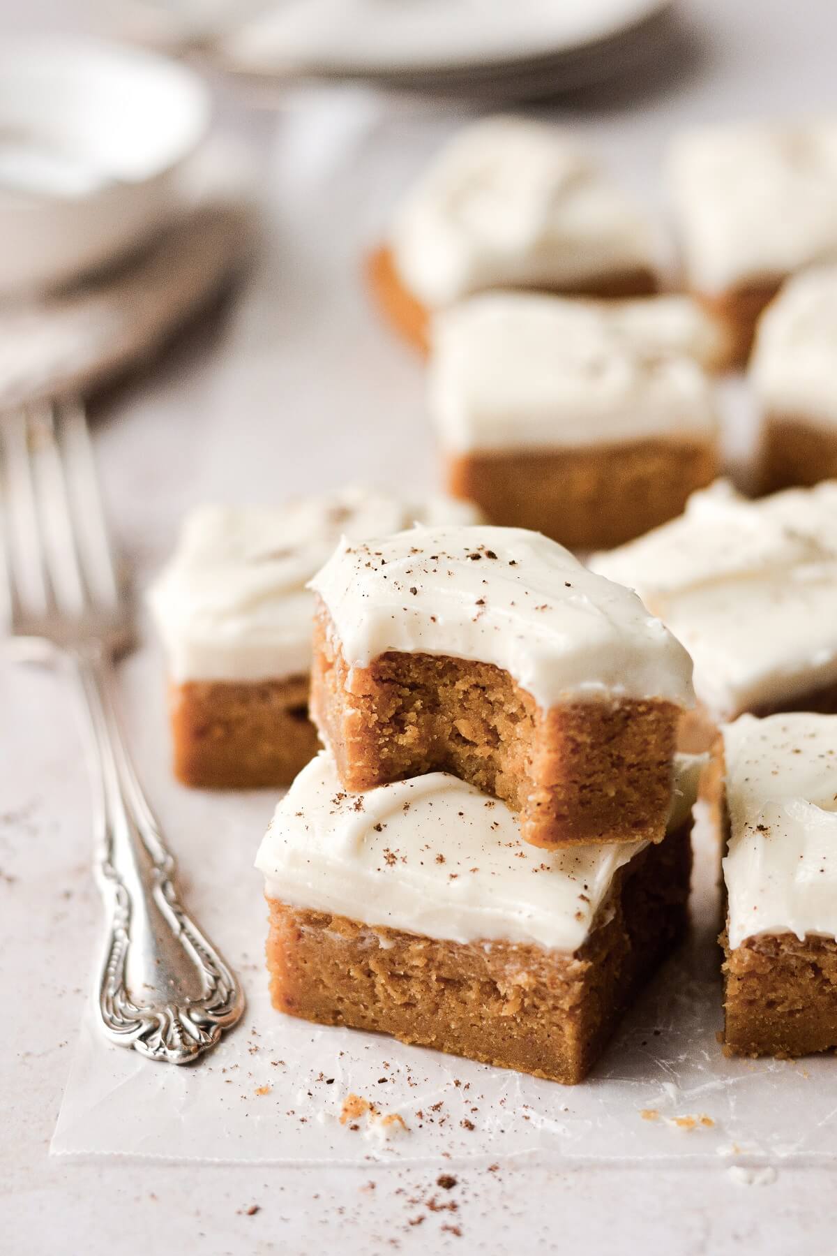 Pumpkin bars cut into squares, one with a bite taken.