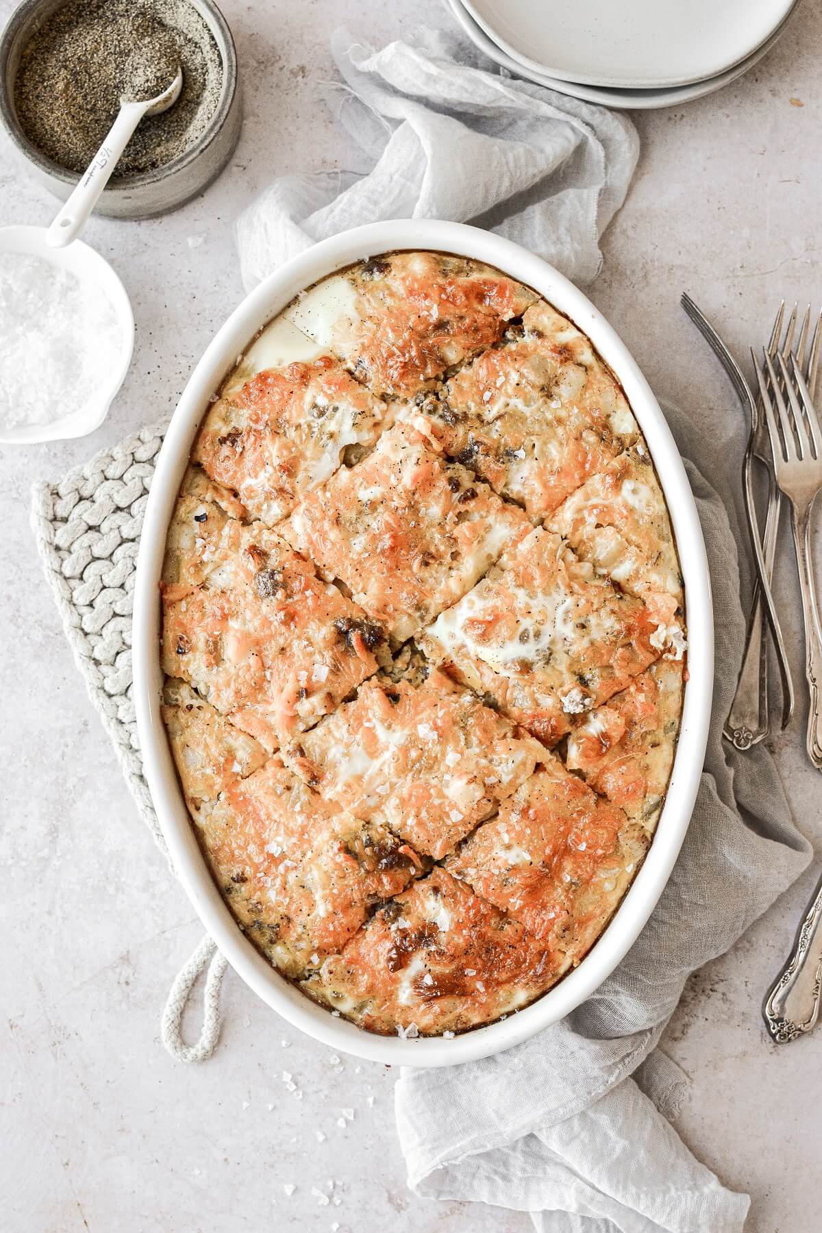 Sausage hashbrown breakfast casserole cut into pieces in a white oval baking dish.