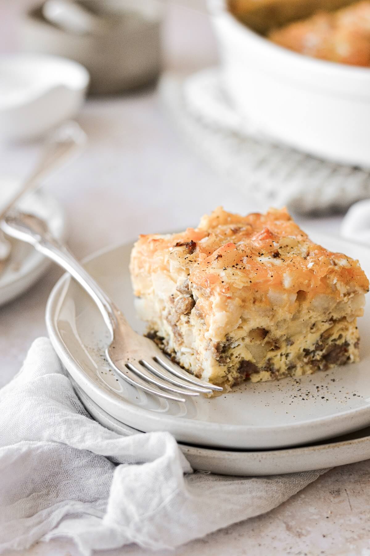 A piece of sausage hashbrown breakfast casserole on a plate.