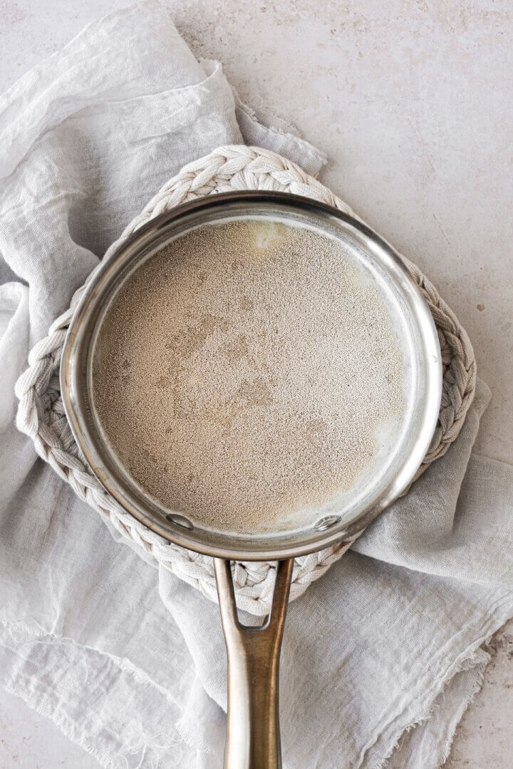 Yeast sprinkled over warm milk in a saucepan.