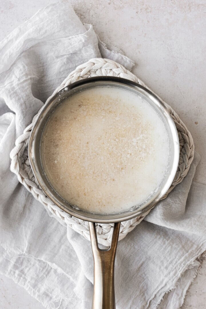 A mixture of yeast and warm milk in a saucepan.