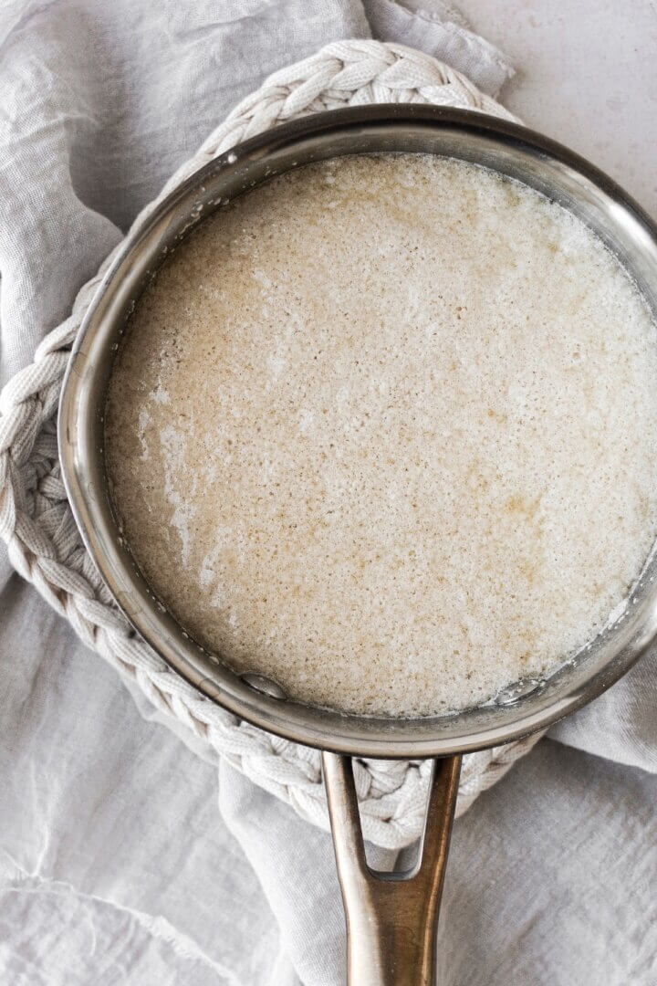 A mixture of yeast and warm milk bubbling in a saucepan.