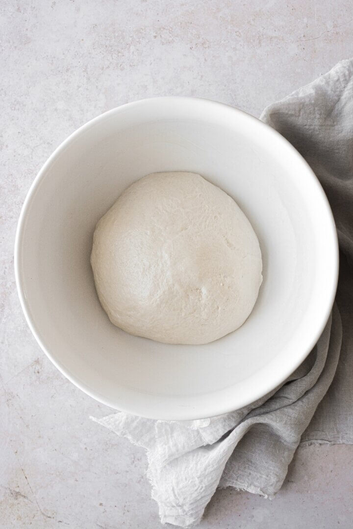 Bread dough rising in a white bowl.