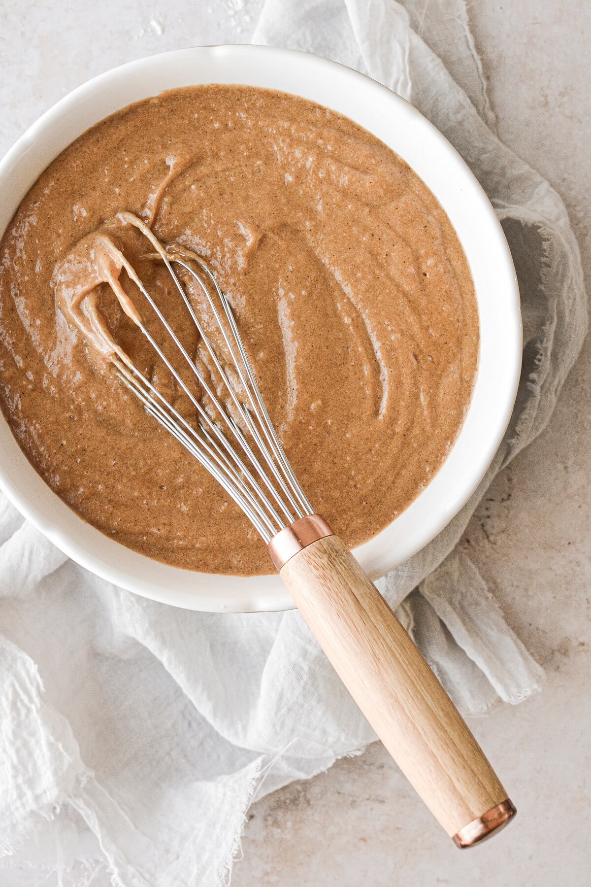A bowl of cake batter and a whisk for a sweet potato bundt cake.
