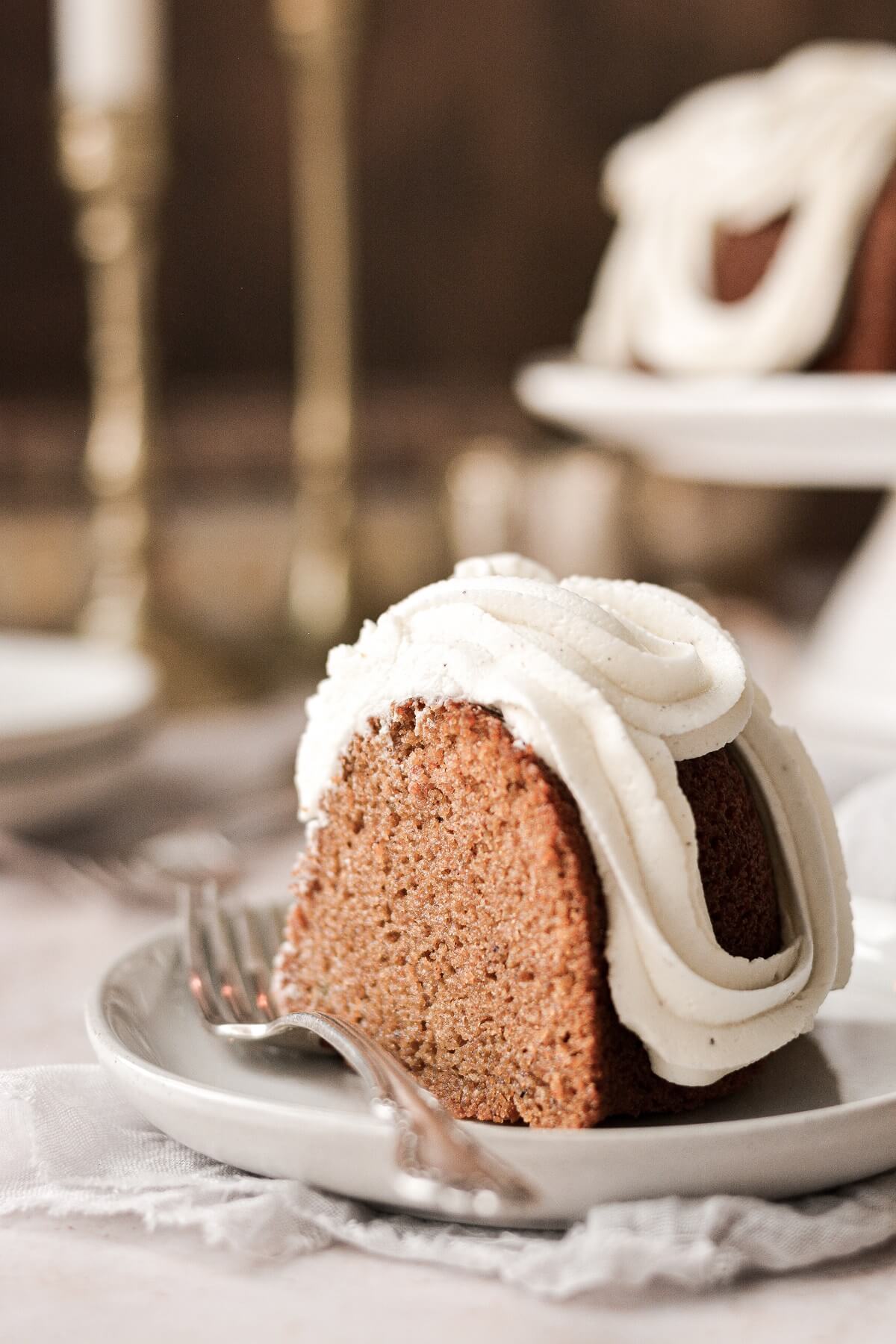 A slice of sweet potato bundt cake with cream cheese buttercream sitting on a plate.